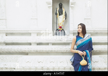 Jeune femme debout devant une figure religieuse Banque D'Images