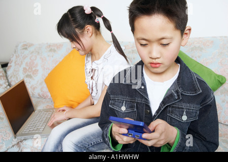 Garçon jouant un jeu vidéo à côté de sa sœur à l'aide d'un ordinateur portable