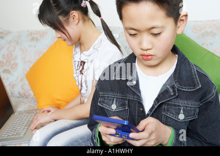 Garçon jouant un jeu vidéo à côté de sa sœur à l'aide d'un ordinateur portable