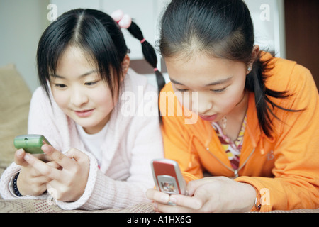 Close-up of two sisters en utilisant les téléphones mobiles Banque D'Images