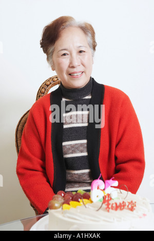 Portrait of a senior woman sitting in front of a birthday cake smiling Banque D'Images