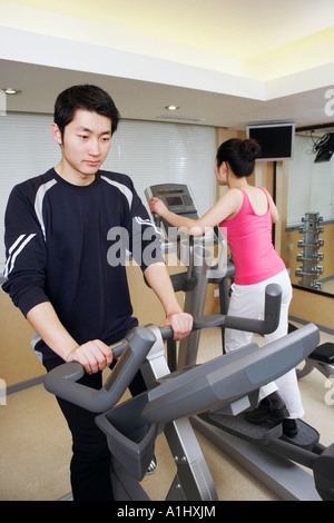 Close-up d'un jeune homme et une jeune femme s'exercer dans une salle de sport Banque D'Images