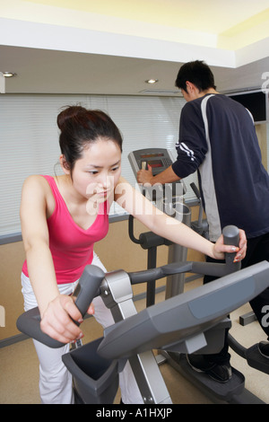 Close-up of a young woman exercising dans une salle de sport avec un jeune homme Banque D'Images
