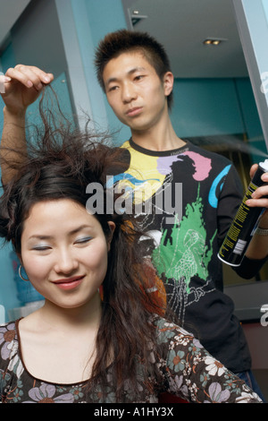 Coiffure homme styling a young woman's hair Banque D'Images