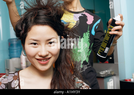 Coiffure homme styling a young woman's hair Banque D'Images
