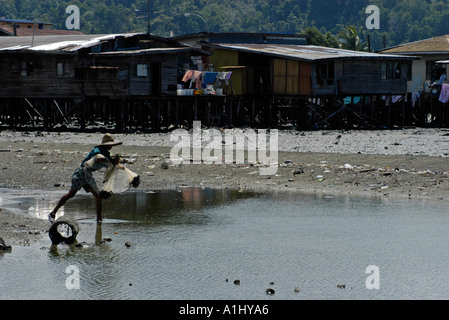 Casting pêcheur malaisien filet devant l'eau du village. Partie d'une séquence. Banque D'Images