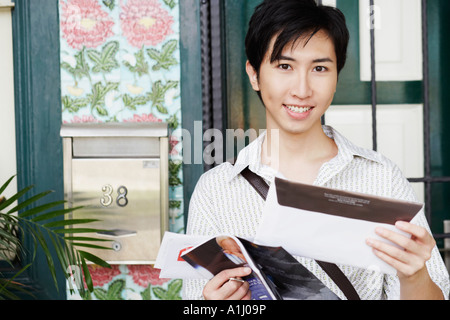 Portrait of a young man holding mail and smiling Banque D'Images