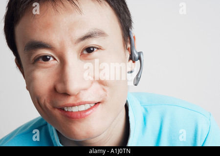 Portrait d'un jeune homme portant un appareil mains libres et souriant Banque D'Images