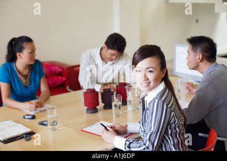 Portrait d'une femme avec trois hommes d'affaires assis à une table de conférence. Banque D'Images