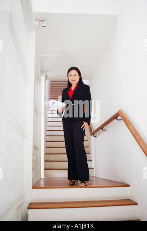 Portrait of a businesswoman carrying rolled up charts and smiling Banque D'Images