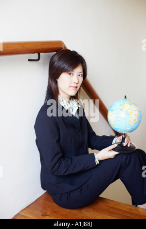 Portrait d'une femme assise sur un escalier et holding a globe Banque D'Images