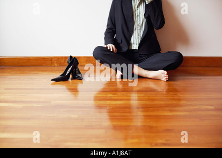 Businesswoman assis en tailleur sur le plancher de bois franc Banque D'Images