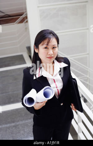 Portrait of a female architect holding rolled up blueprints Banque D'Images