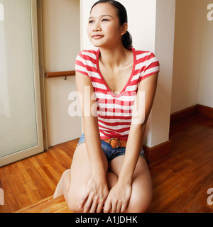 Jeune femme agenouillée sur un plancher de bois dur Banque D'Images