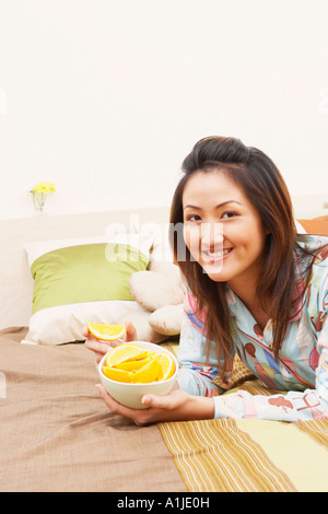 Portrait d'une jeune femme tenant un bol de tranches de citron et souriant Banque D'Images