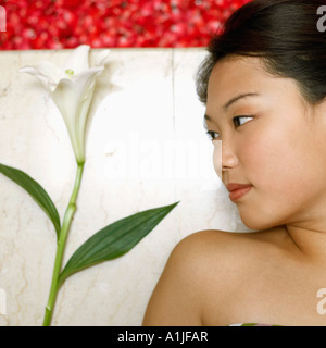Portrait d'une jeune femme étendue sur le sol près d'un bain à remous rempli de pétales de rose
