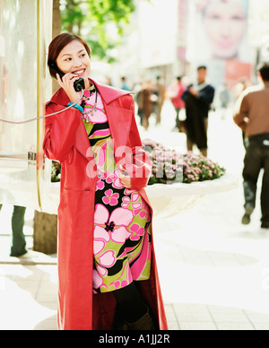 Jeune femme parlant sur un téléphone public Banque D'Images