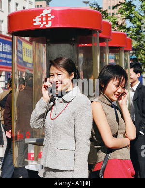 Jeune femme parlant sur un téléphone avec une autre jeune femme parlant sur un téléphone mobile Banque D'Images