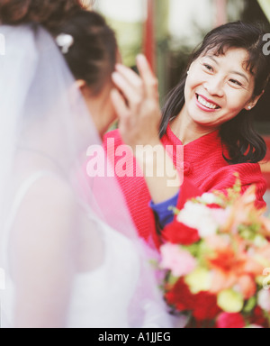 Réglage de la jeune femme les cheveux d'une autre femme dans la robe de mariage Banque D'Images