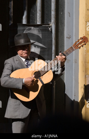 Vieil homme jouant avec la guitare sur le trottoir (en face de l'image de Carlos Gardel) B Banque D'Images