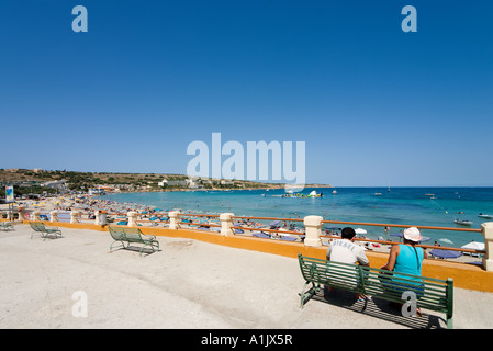 Couple sittiing sur un banc sur le front de mer de la baie de Mellieha, Malte Banque D'Images