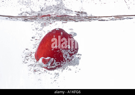 Pomme fruit est tombé dans l'eau faire splash Banque D'Images