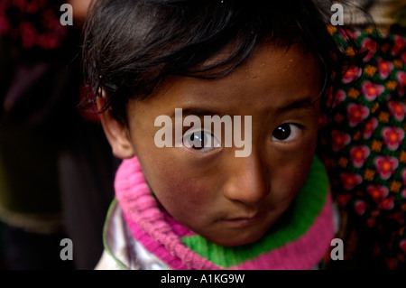 Un petit tibétain fille avec d'autres pèlerins line jusqu'à rendre hommage à la Temple du Jokhang à Lhassa Tibet Chine 19-OCT-2006 Banque D'Images