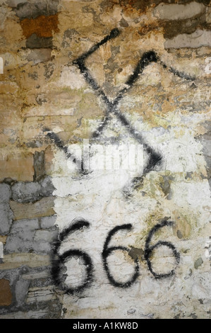 Le swastika et 666 nombre de la bête ou l'antéchrist de l'écriture graffiti peint sur un mur d'une maison déserte Banque D'Images