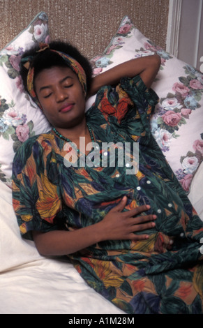 Femme noire/Africaine en fin de grossesse couchée sur un canapé ayant reste Banque D'Images