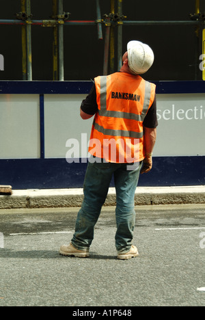 London City of westminster chantier avec pontier-élingueur debout dans la voie publique supervisant la descente de crane skip Banque D'Images