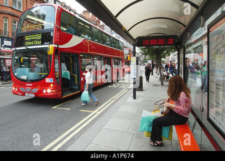 Oxford Street 137 London bus à impériale rouge à l'arrêt de bus des transports publics dans la rue commerçante, siège du refuge et embarquement des passagers dans le West End England UK Banque D'Images