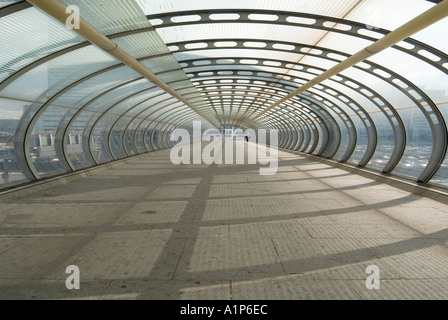 Passerelle piétonne à l'intérieur d'acier translucide structure tunnel tubulaire effet écrasée par la manipulation Banque D'Images