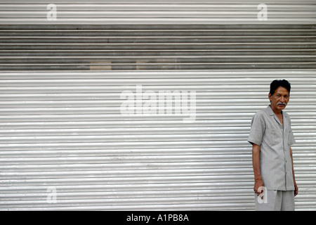 Un homme se tient devant un magasin fermé à New Delhi en Inde. Banque D'Images