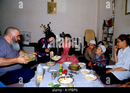 Clapton London famille musulmane assis sur le sol repas manger Père verser la boisson pendant Ramadam Banque D'Images