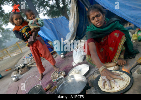 Les femmes un cuit les aliments à l'extérieur d'une tente dans une brèche à New Delhi en Inde. Banque D'Images