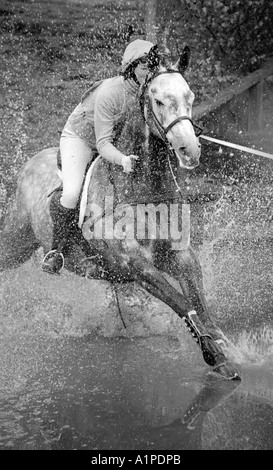 Cavalier et son cheval dans de l'eau splash sur saut à cheval d'essais cliniques. Banque D'Images