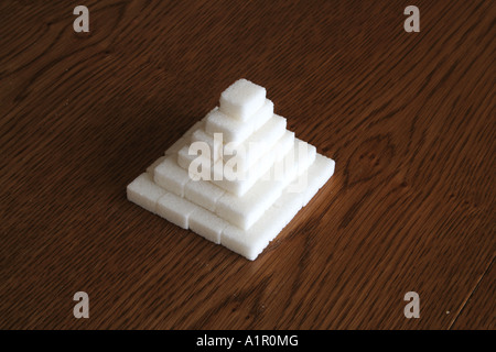 Pile de cubes de sucre disposés en forme de pyramide sur une table en bois. Banque D'Images