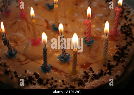 Gâteau d'anniversaire avec bougies allumées, garniture de caramel et saupoudrées de chocolat. Banque D'Images