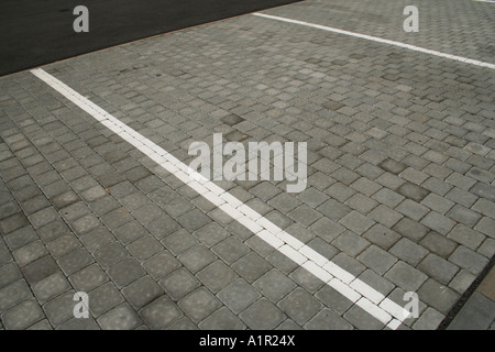 Aire de stationnement vide avec trottoir en brique et lignes blanches marquant les places de stationnement. Banque D'Images