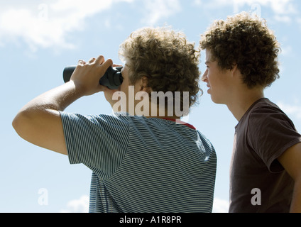 Deux jeunes hommes à la vue à l'aide de jumelles vue arrière Banque D'Images