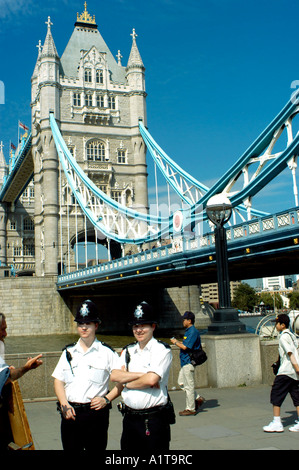 Londres, Angleterre, vue sur Tower Bridge avec deux officiers de police, Bobbies en uniforme traditionnel, debout près de la rivière Thames Banque D'Images