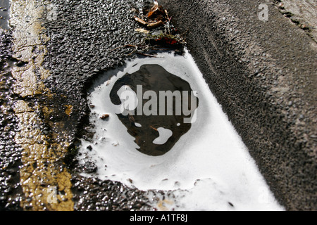 Flaque d'eau sur le côté de la route de laver la voiture avec des bulles de savon Banque D'Images