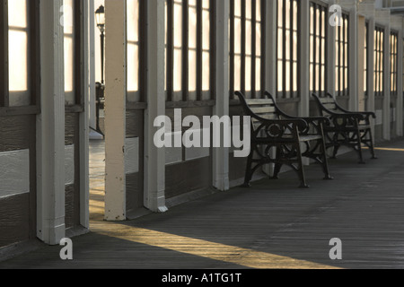 Tôt le matin soleil projette des ombres sur les bancs vides / sièges. Banque D'Images