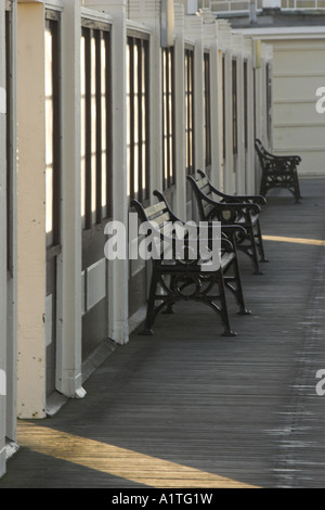 Tôt le matin soleil projette des ombres sur les bancs vides / sièges. Banque D'Images