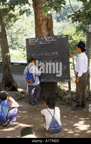 COMMUNIDAD SEGUNDO MONTES BOY TRAVAILLANT SUR LES MATHÉMATIQUES SUR UN TABLEAU NOIR À L'EXTÉRIEUR. EL SALVADOR 1992 Banque D'Images