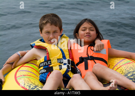 Garçon et une fille assise sur un radeau dans l'eau du lac de Biscarrosse en France Banque D'Images