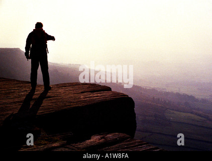 Walker sur Bamford Edge sur un jour d'hiver brumeux dans le Derbyshire Peak District England UK Banque D'Images