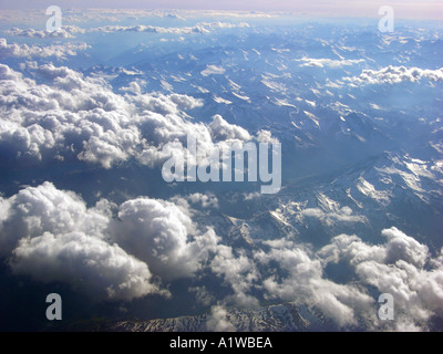Les alpes haut dans le ciel les nuages en altitude formations vu de dessus d'une fenêtre de l'avion survole LES ALPES Banque D'Images