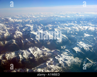Les alpes haut dans le ciel les nuages en altitude formations vu de dessus d'une fenêtre de l'avion survole LES ALPES Banque D'Images