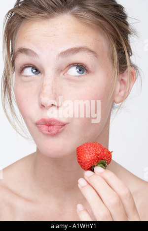 Portrait of a young woman eating a strawberry Banque D'Images